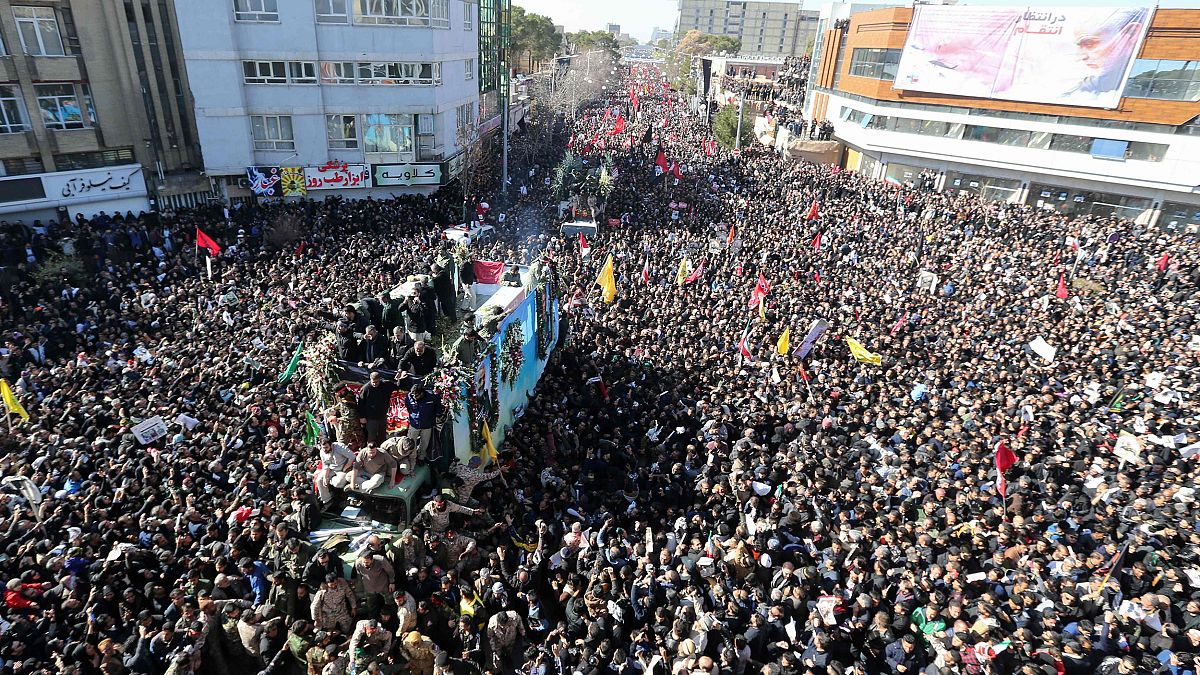 Image: Iranian mourners gather around a vehicle carrying the coffin of slai