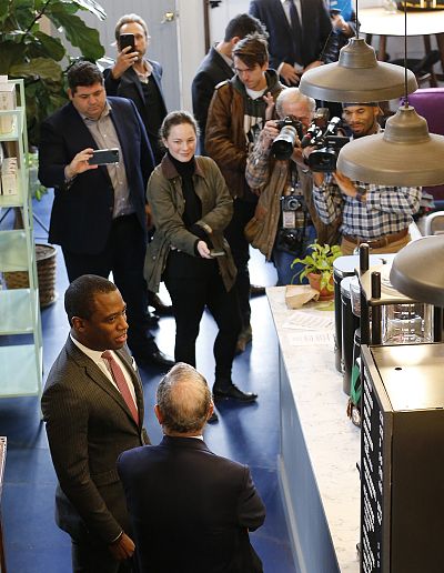 Democratic presidential candidate, former New York Mayor Michael Bloomberg, front back to camera, chats with Richmond mayor Levar Stoney, front left, under the watchful eye of the media at a coffee shop in Richmond, Va. on Jan. 7, 2020.