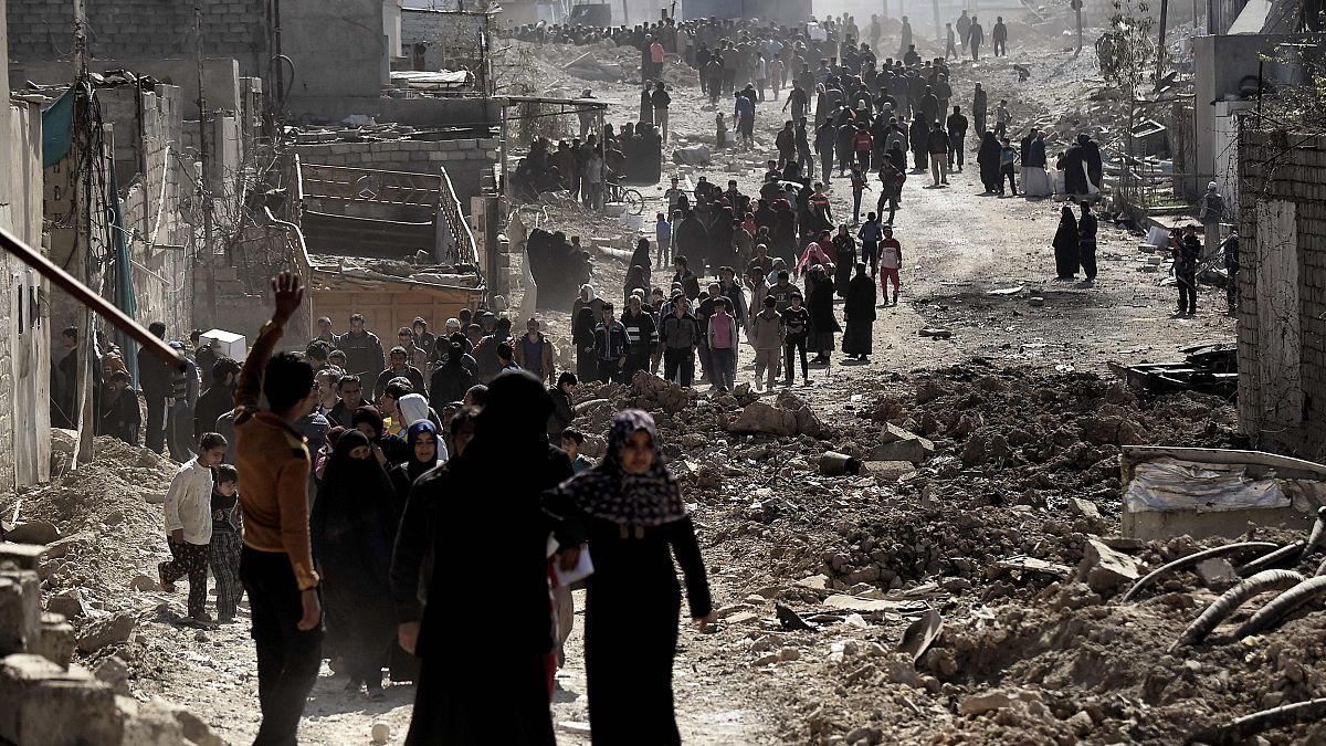 Image: People walk in west Mosul after a food distribution from the Iraqi t