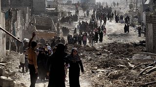 Image: People walk in west Mosul after a food distribution from the Iraqi t