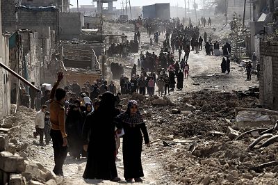 People walk west in Mosul after Iraqi troops distribute food on March 10, 2017, during the battle to seize the city from ISIS.