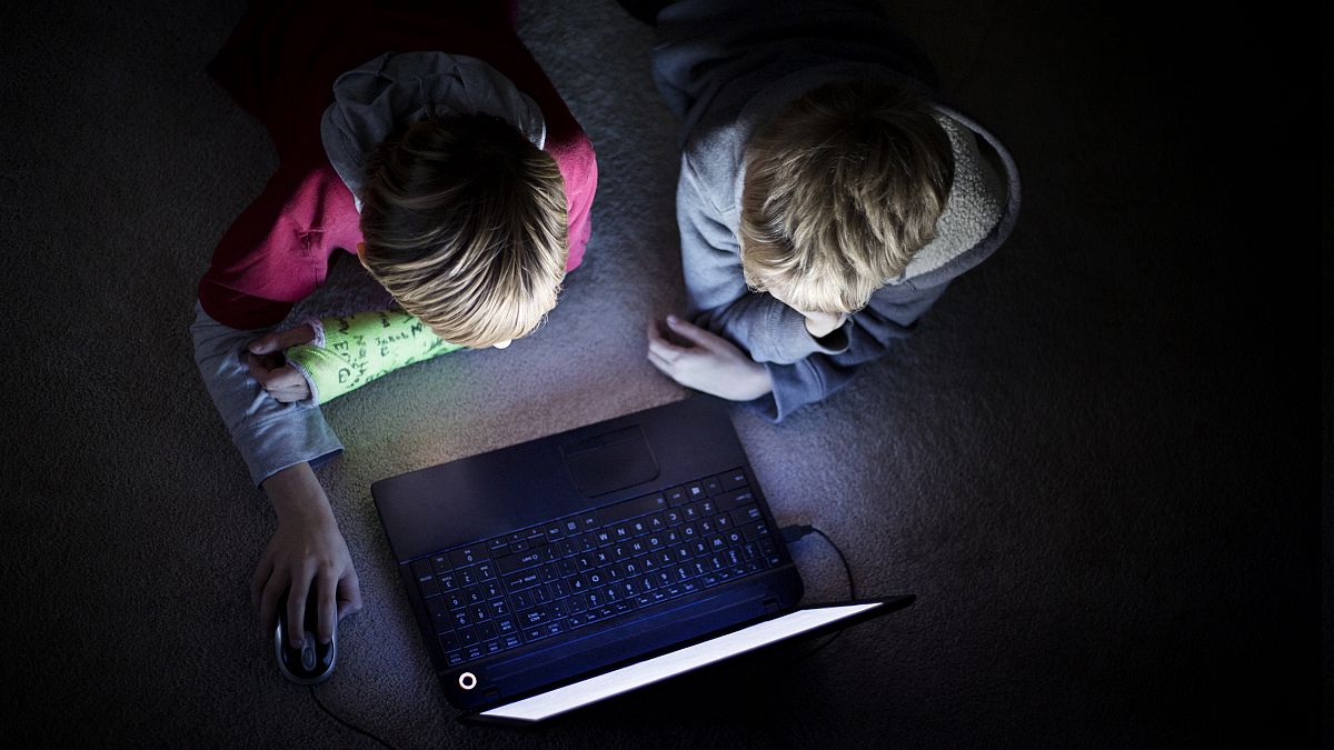 Image: Two boys using laptop in dark room