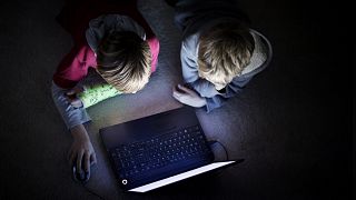 Image: Two boys using laptop in dark room
