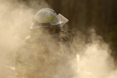 A firefighter covers his face from black smoke as he battles a wildfire near Bendalong, Australia on Jan. 3, 2020.
