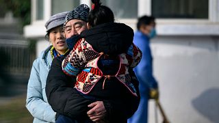 Image: A man holding her daughter leaves the Wuhan Medical Treatment Centre