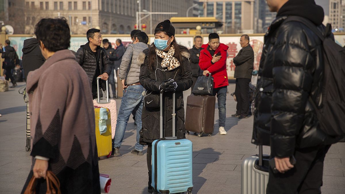 Image: A traveler wears a facemask as she stands near the Beijing Railway S