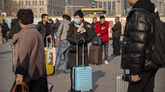 Image: A traveler wears a facemask as she stands near the Beijing Railway S