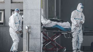 Image: Medical staff members carry a patient into the Jinyintan hospital, w