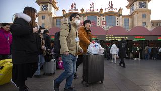Image: A traveler wears a face mask as he walks outside Beijing Railway Sta