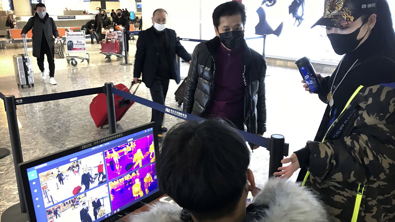Image: Travelers pass through a health screening checkpoint at Wuhan Tianhe