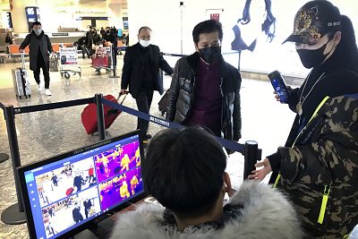 Travelers pass through a health screening checkpoint at Wuhan Tianhe International Airport on Tuesday.
