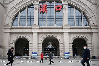 People walk past the closed Hankou Railway Station in Wuhan on Thursday after the city was locked down following the outbreak of a new coronavirus. 