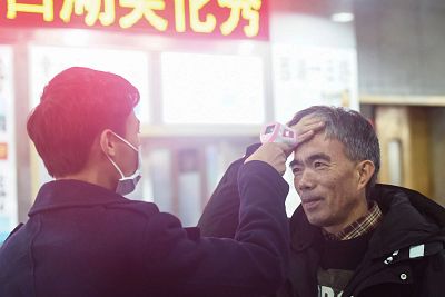 A staff member checks the body temperature of a passenger after a train from Wuhan arrived in Hangzhou, China\'s eastern Zhejiang province, on Thursday. 