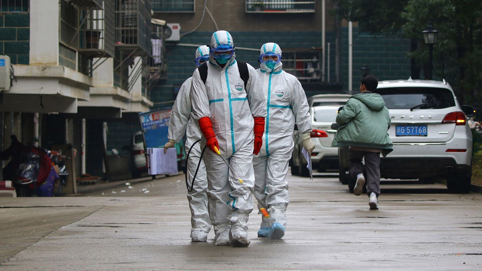 Image: Workers wearing protective clothing disinfect a residential area in 