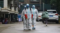 Image: Workers wearing protective clothing disinfect a residential area in 