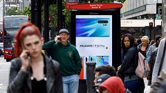 Image: Pedestrians use their mobile phones near a Huawei advert at a bus st