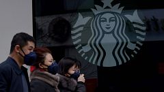 Image: People wearing protective face masks walk past a closed Starbucks co