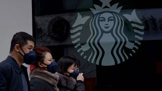Image: People wearing protective face masks walk past a closed Starbucks co