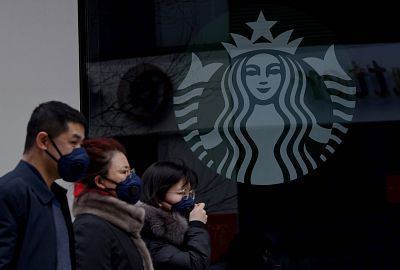 People wearing protective face masks walk past a closed Starbucks coffee shop at a grocery in Beijing on Jan. 29, 2020.