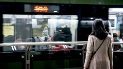 Image: A woman wears a protective mask while waiting for the subway in the 