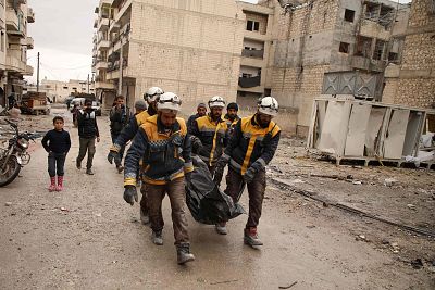 White Helmets volunteers carry the body of a woman recovered from the rubble after an airstrike in the town of Ariha in Idlib Thursday.
