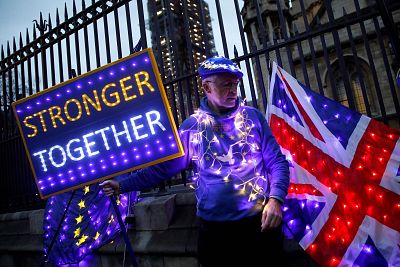 Anti-Brexit protester holds illuminated Union and E.U. flags near the Houses of Parliament in London.