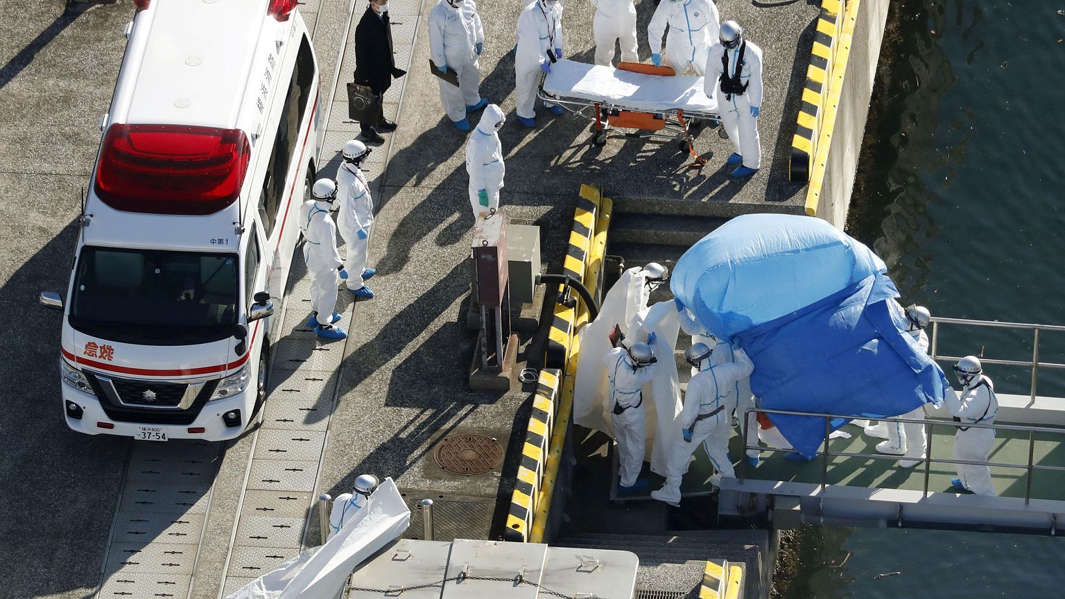 Image: Officers in protective gear escort a person who was on board cruise 