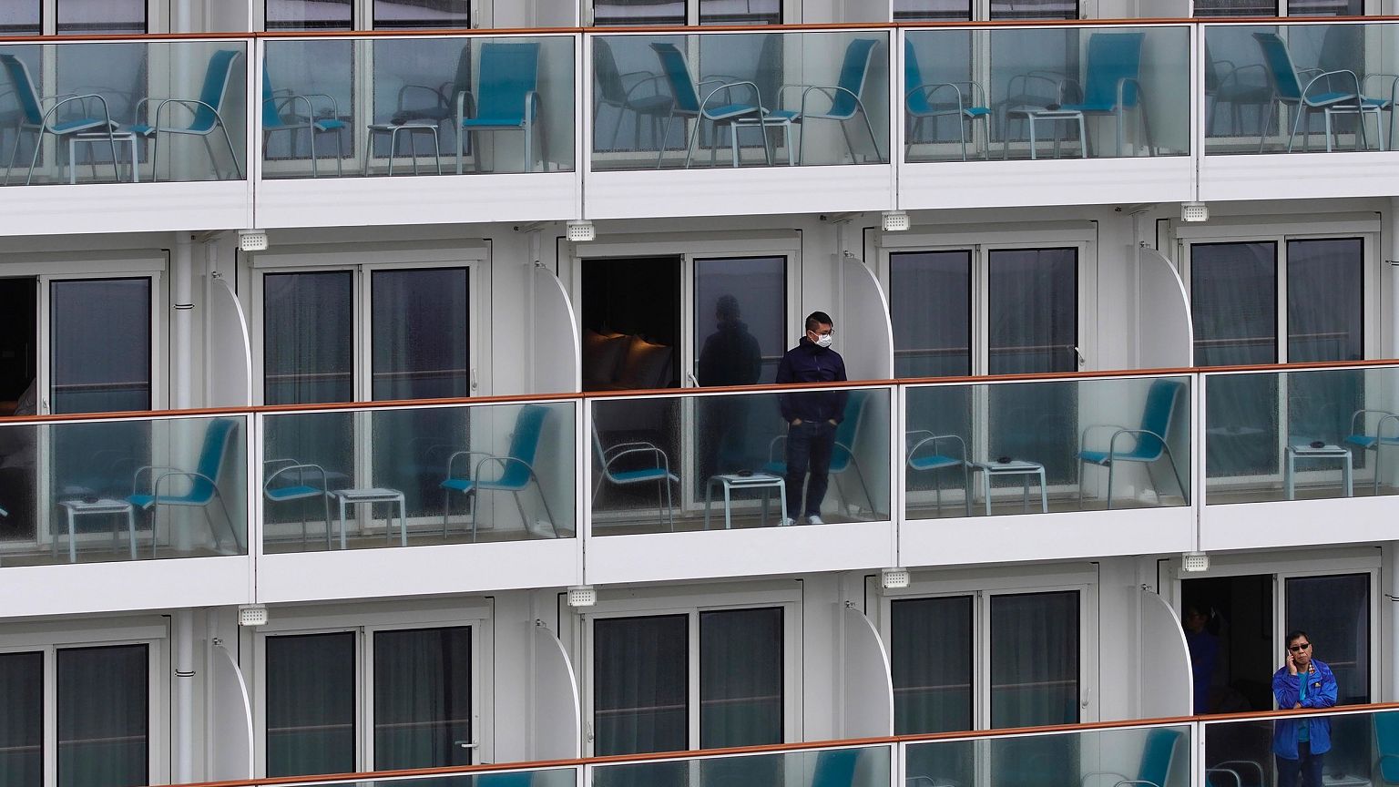 Image: Passengers look out from the World Dream cruise ship docked at Kai T