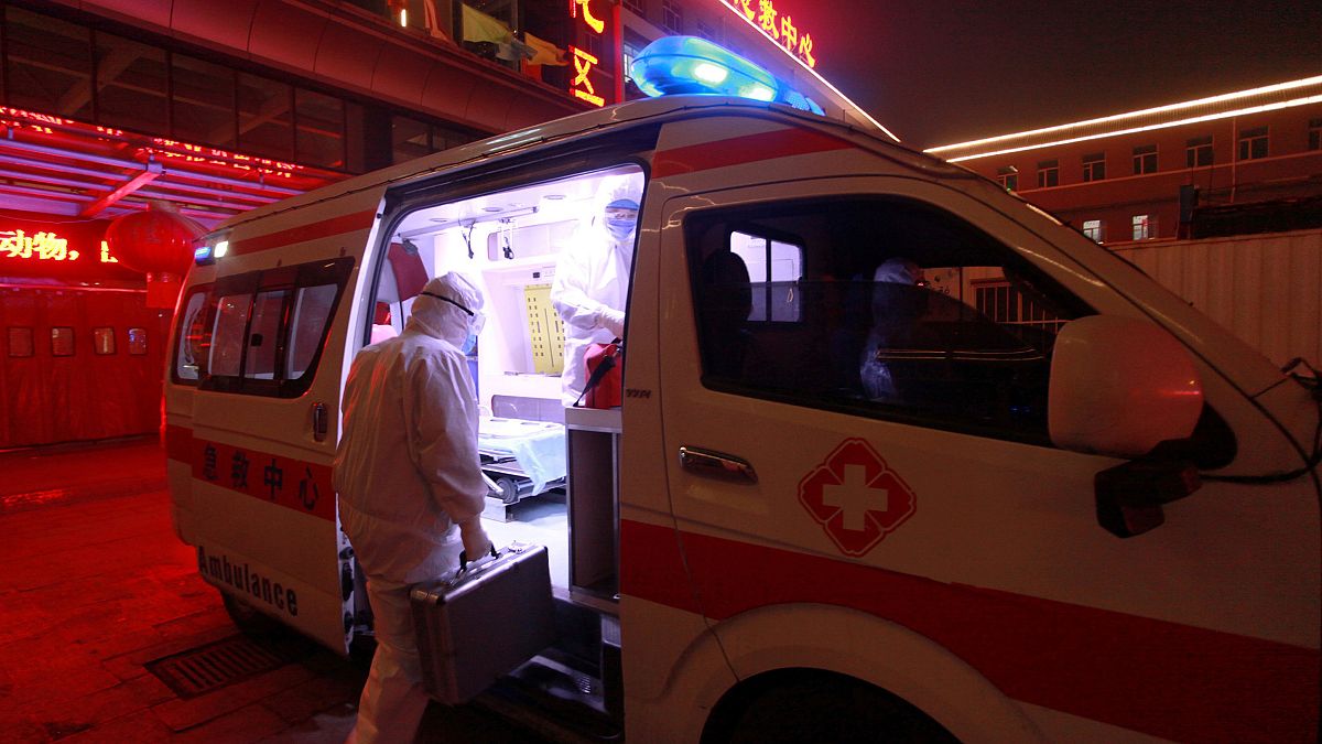 Image: A medical worker in protective suit gets onto an ambulance at a hosp