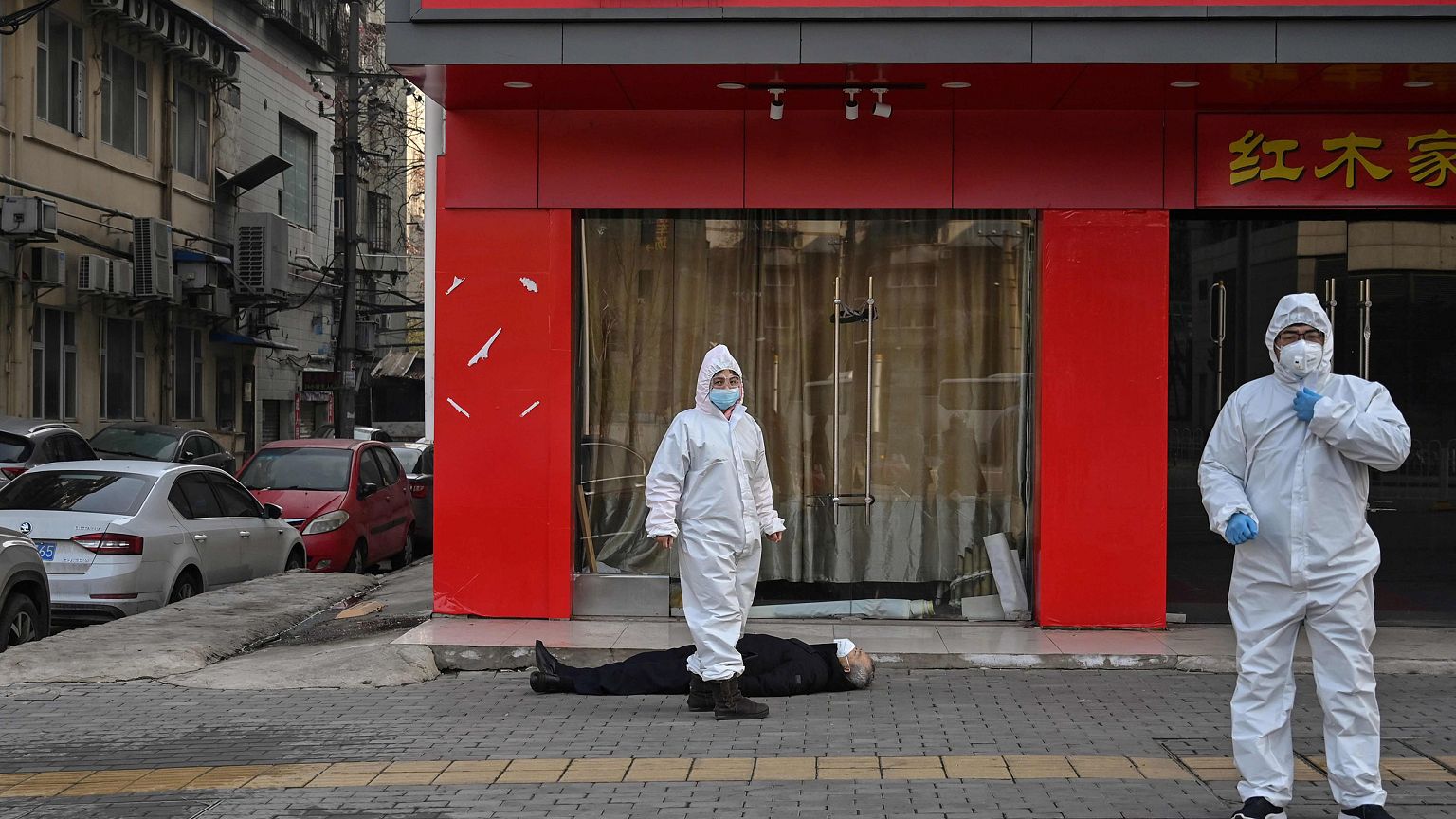 Image: Officials in protective suits checking on an elderly man wearing a f