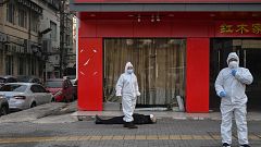 Image: Officials in protective suits checking on an elderly man wearing a f