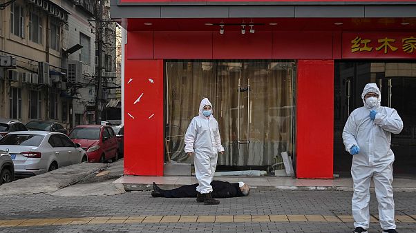 Image: Officials in protective suits checking on an elderly man wearing a f Image: Officials in protective suits checking on an elderly man wearing a f