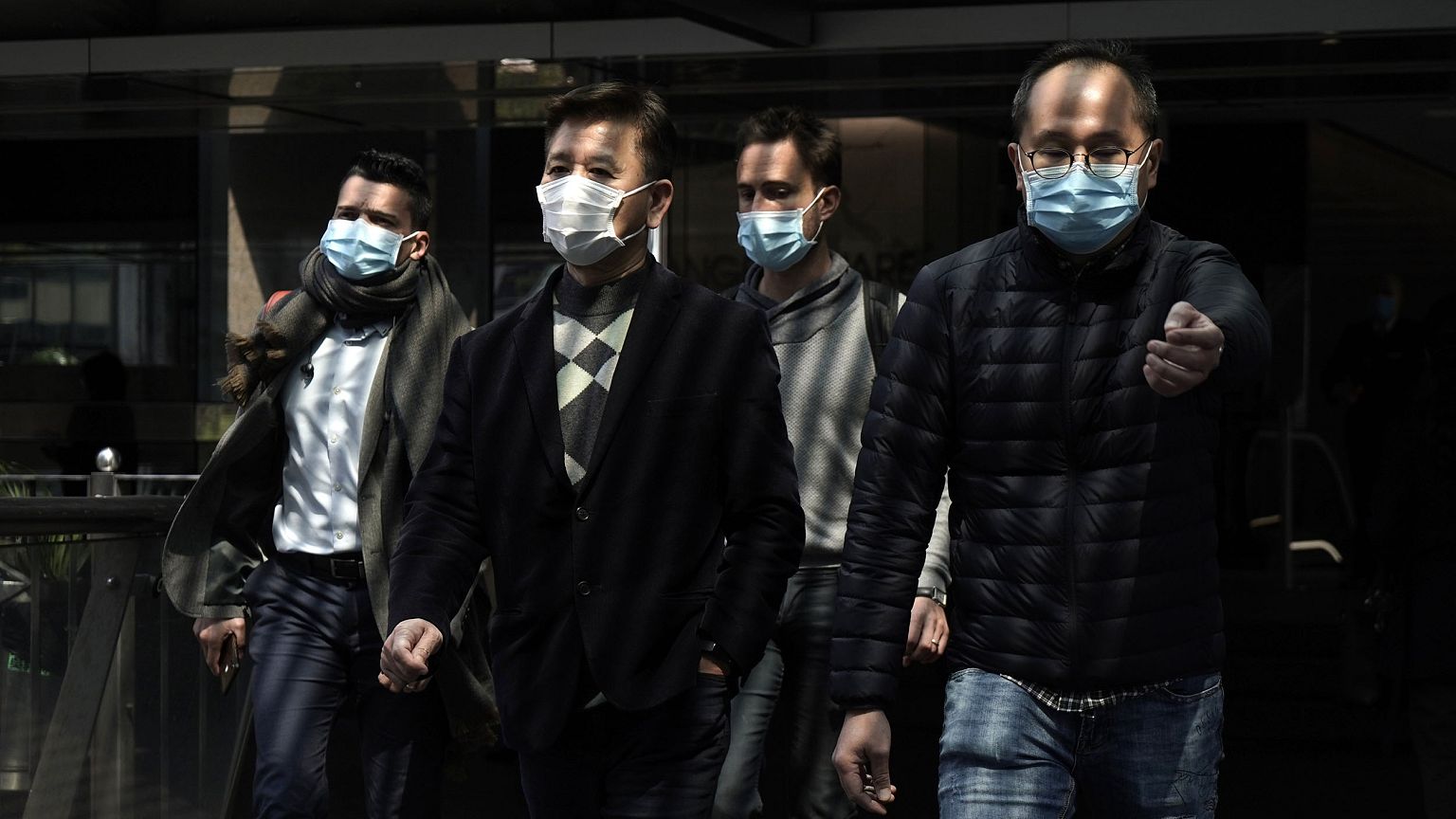 Image: People wearing masks walk in Central, a business district in Hong Ko