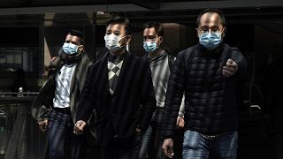 Image: People wearing masks walk in Central, a business district in Hong Ko