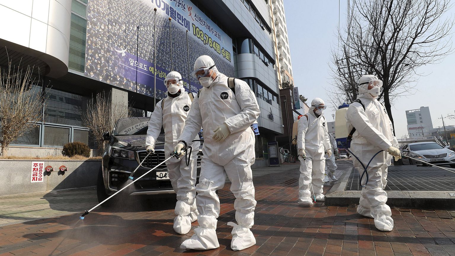 Image: Workers wearing protective gears spray disinfectant against the new 