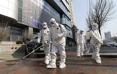 Workers wearing protective gear spray disinfectant in front of a church in Daegu, South Korea, on Thursday. 