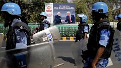 Image: Military personnel patrol near a sign featuring President Donald Tru