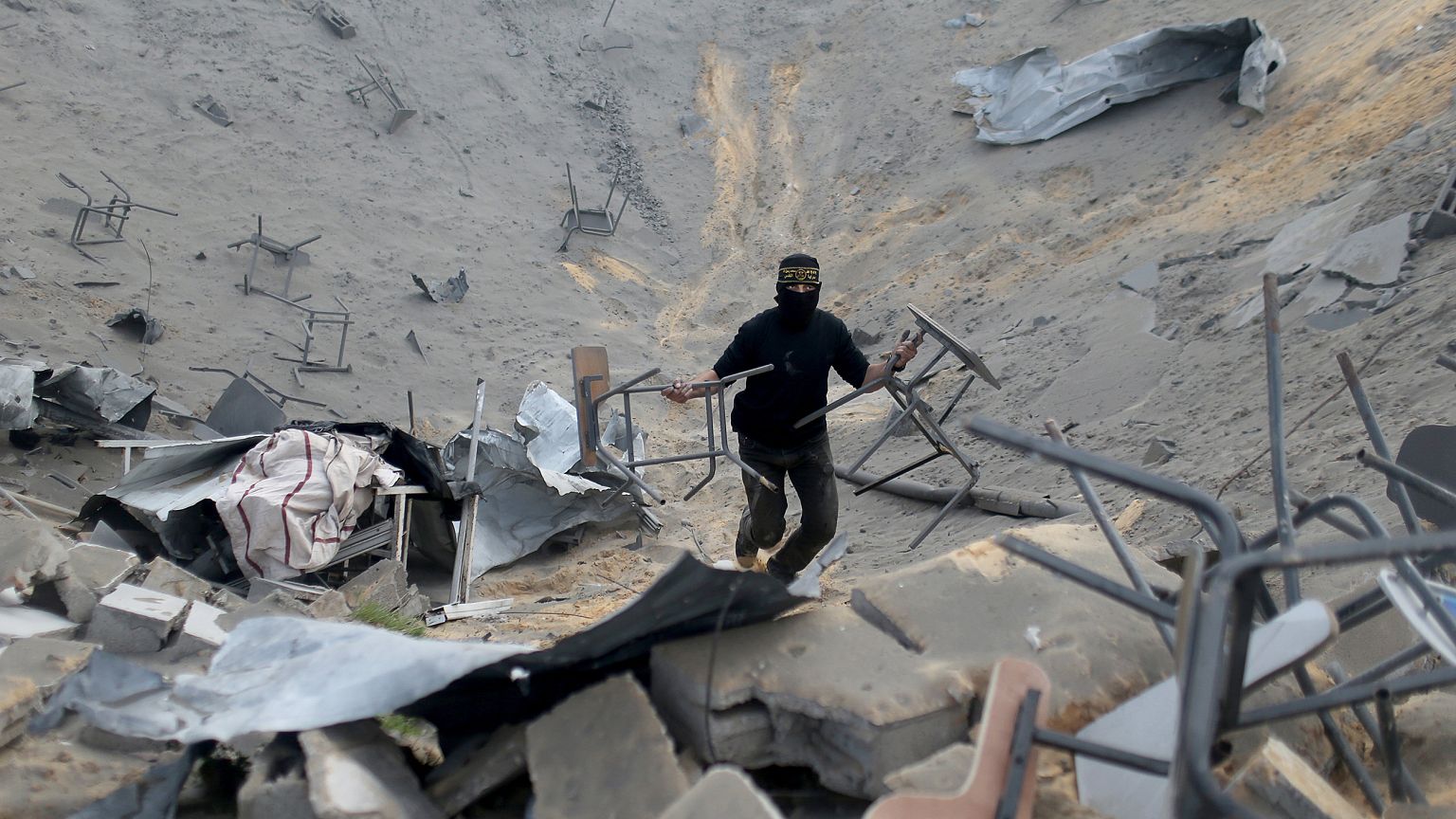 Image: A Palestinian militant carries chairs as he surveys an Islamic Jihad
