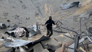 Image: A Palestinian militant carries chairs as he surveys an Islamic Jihad