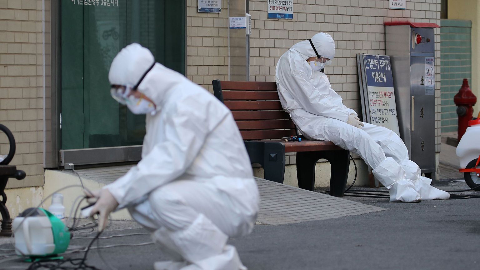 Image: A medical worker wearing protective gear takes a rest as he waits fo