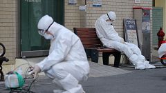 Image: A medical worker wearing protective gear takes a rest as he waits fo