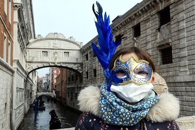 A young tourist wearing a protective face mask and a Carnival mask visits the streets of Venice, Italy on Monday. 