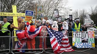 Image: Demonstrators hold signs behind a barricade in support of WikiLeaks