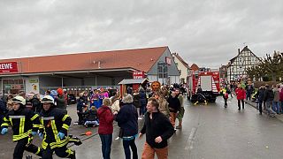 Image: People react at the scene after a car drove into a carnival parade i