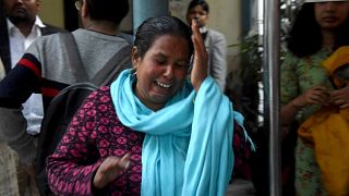 Image: A woman sobs at the sight of her husband, who was shot in the face w