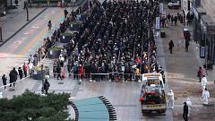 Image: People wait in line to buy face masks outside a department store in 