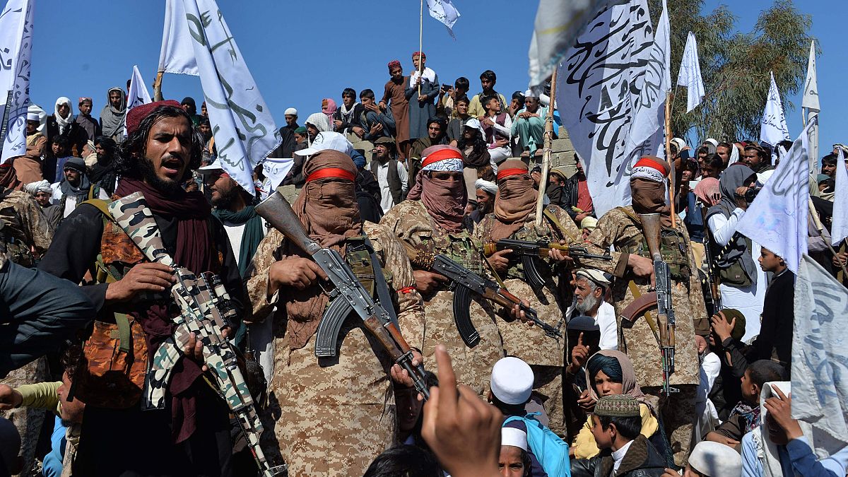 Image: Afghan Taliban militants and villagers attend a gathering as they ce