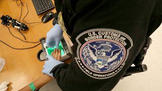 Image: A woman who is seeking asylum has her fingerprints taken by a U.S. C