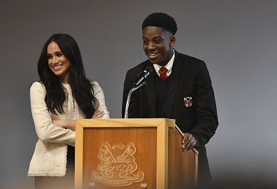 Meghan looks on after handing the podium at a school to student Aker Okoye to discuss the importance of International Women\'s Day. Friday\'s visit marked her last solo engagement as a working royal.