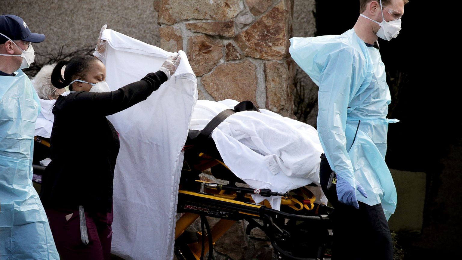 Image: Medics transport a patient to an ambulance from the Life Care Center